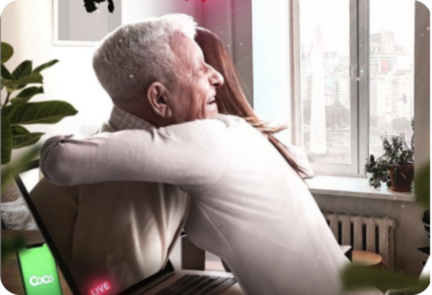 Nieta abrazando a su abuelo através del monitor de una notebook, junto a la notebook un celular ejecutando la app de Coco Mercado